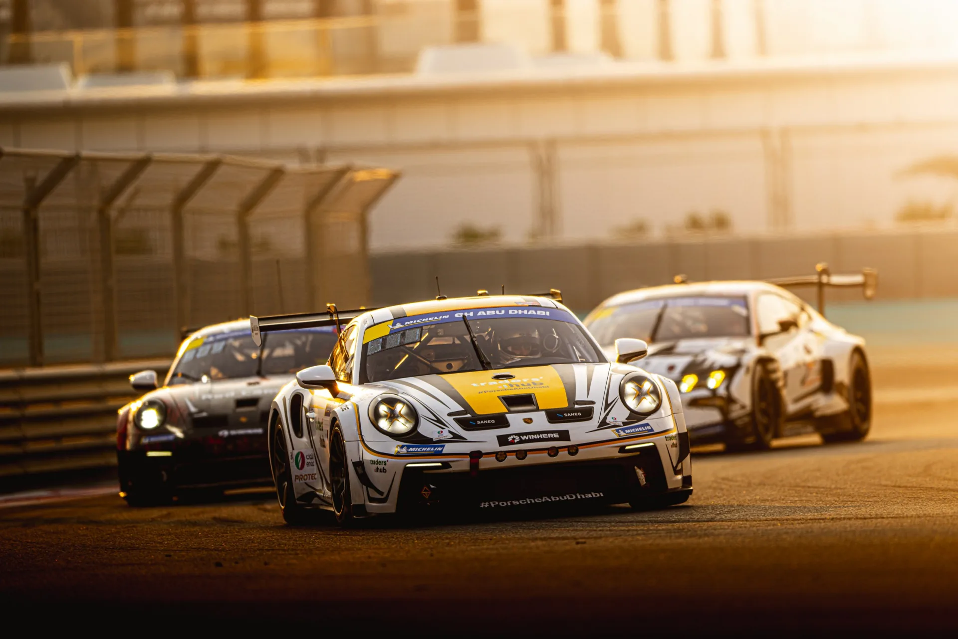 The Rabdan Motorsport Porsche 911 GT3 Cup leading two rivals through a corner at golden hour during the 6H Abu Dhabi at Yas Marina